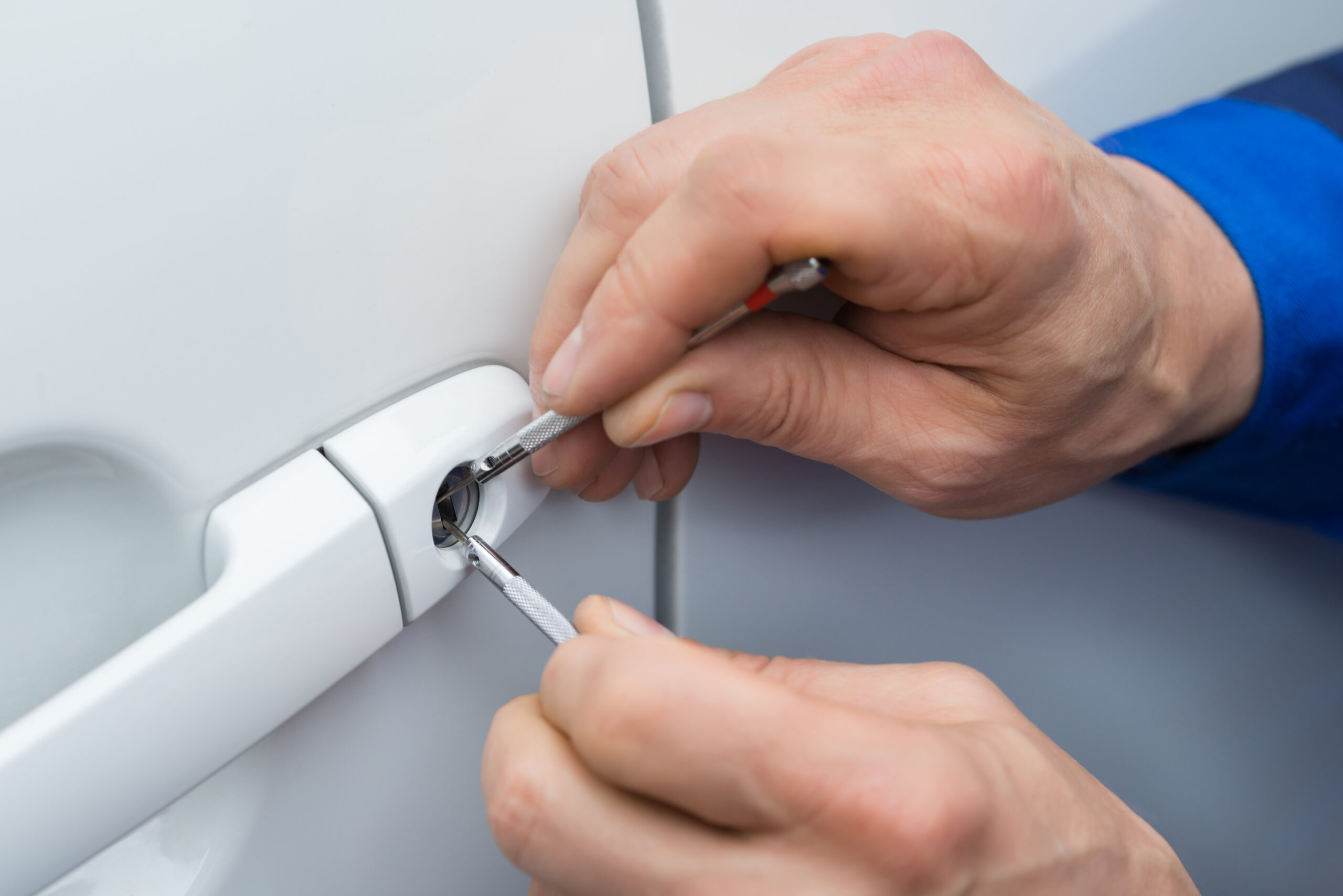 Close-up Of Person Hand Holding Lockpicker To Open Car Door